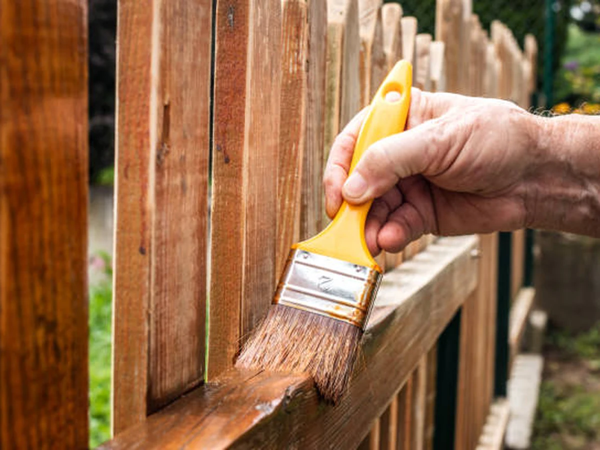 Hand brush applying fence paint to timber panels by Hereford Painters